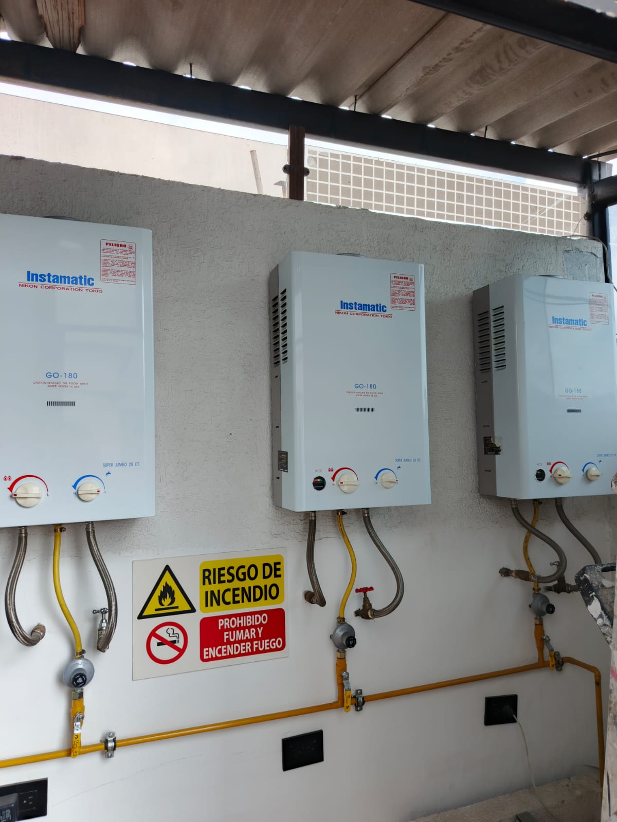 Tres calefones Instamatic GO-180 instalados con cartel de seguridad