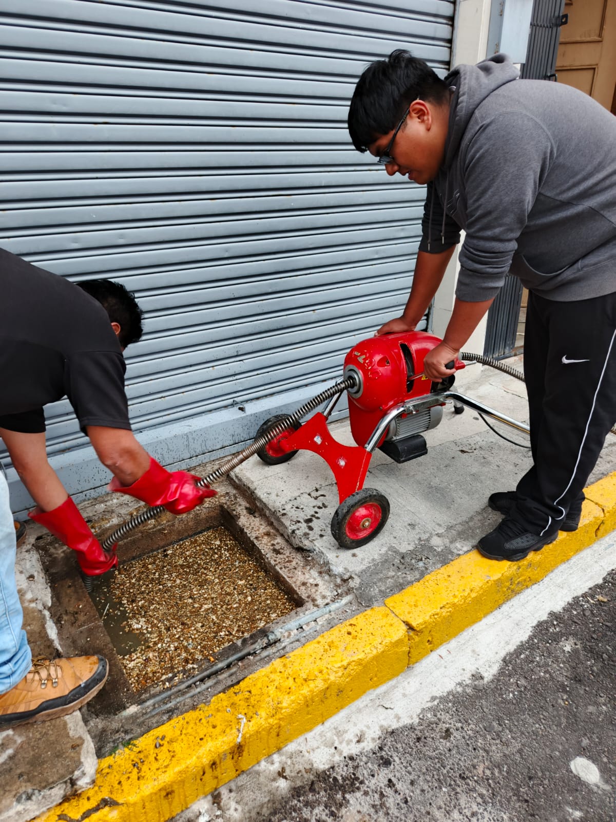 Equipo realizando destape de cañería en acera
