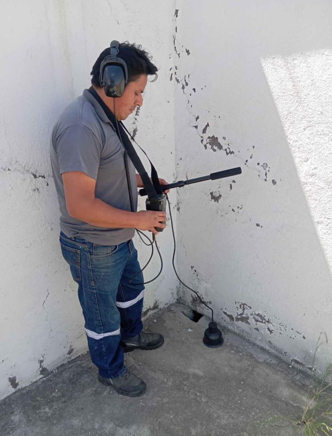 Técnico con audífonos detectando fugas de agua con geófono